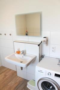 a white bathroom with a sink and a washing machine at Zur Strandwiese W2 in Dahme