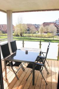 a table and chairs on a deck with a view of the water at Zur Strandwiese W4 in Dahme
