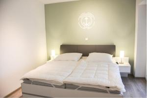 a bedroom with a large white bed with two lamps at Zur Strandwiese W3 in Dahme