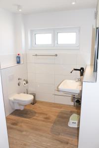 a white bathroom with a toilet and a sink at Zur Strandwiese W3 in Dahme