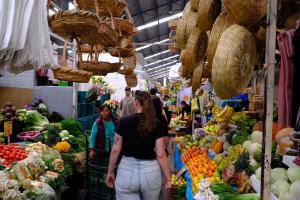 a group of people walking through a market with fruits and vegetables at Casa Pepe in Puebla