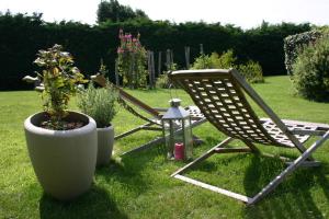 two lawn chairs and a plant in a yard at Ferme Saint Christophe in Saint-Marcan