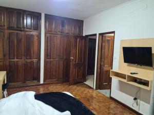 1 dormitorio con armarios de madera, TV y cama en Pastello guest house, en Maputo