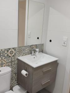 a bathroom with a sink and a toilet and a mirror at Anduriña in Vigo