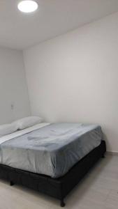 a bed in a bedroom with a white wall at Apartamento in Medellín