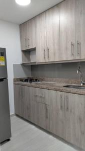 Apartamento في ميديلين: مطبخ مع دواليب خشبية وثلاجة حديد قابلة للصدأ
