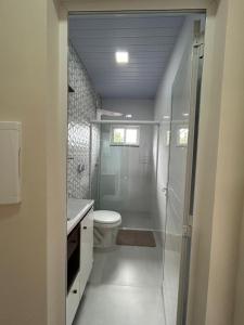 a bathroom with a toilet and a glass shower at Aconchego, no melhor lugar de Foz! in Foz do Iguaçu