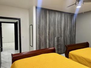 a bedroom with two beds and a yellow blanket at DEPARTAMENTOS ARTICULO 123 - departamento #1 in Tijuana
