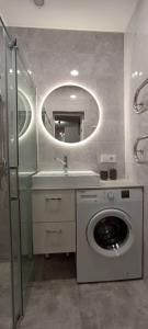 y baño con lavadora y espejo. en Ramūs apartamentai, en Anykščiai