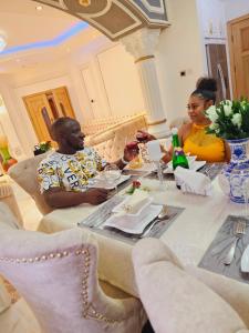 un hombre y una mujer sentados en una mesa con copas de vino en Serene villaz en Kampala