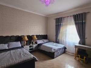 1 dormitorio con 2 camas y ventana en Serene villaz en Kampala