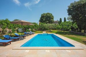 a swimming pool with chairs and an umbrella at Villa Altura in Valtura