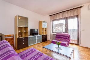 uma sala de estar com mobiliário roxo e uma televisão em Apartment Jovanka em Medulin