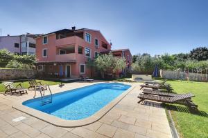 a swimming pool with chairs and a house at House Aldo in Banjole