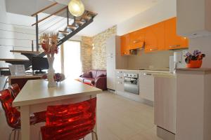 a kitchen with orange cabinets and a table with red chairs at Villa Blue II in Banjole