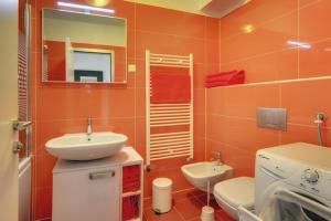 an orange bathroom with a sink and a toilet at Apartment City Business in Pula +14 photos