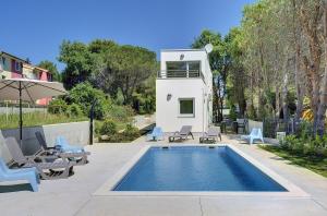 uma piscina com cadeiras e uma casa em Villa Chiara em Premantura