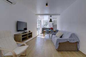 uma sala de estar com um sofá e cadeiras e uma televisão em Villa Chiara em Premantura