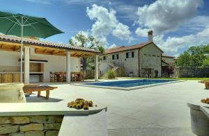 un patio trasero con piscina y una casa con sombrilla en Villa Lucy, en Rojnići
