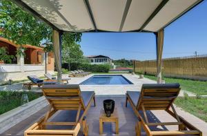 a patio with chairs and a swimming pool at Villa Maria Betiga in Peroj