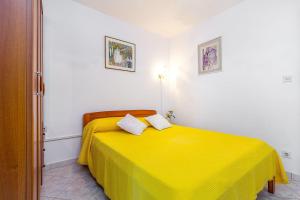 a bedroom with a yellow bed with two pillows at Fernando in Peroj