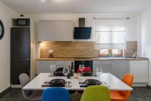 a kitchen with a white table and chairs and a kitchen with white cabinets at Holiday House Ulika in Loborika