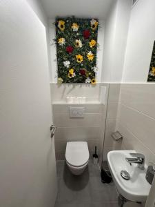 a bathroom with a toilet and a flower painting on the wall at Apartman Trsat in Rijeka +9 photos