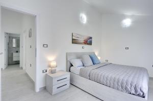 a white bedroom with a bed and a night stand with a lamp at 500 Meter zum Strand mit Privatpool, Meerblick, Klima, WLAN in Ližnjan +17 photos