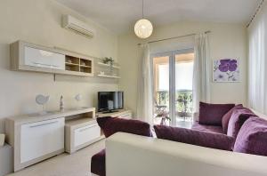 ein Wohnzimmer mit einem lila Sofa und einem TV in der Unterkunft Modernes Appartement mit Balkon, BBQ, WLAN, Klima in Vodnjan
