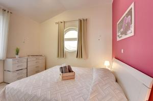 ein Schlafzimmer mit einem Bett und einer rosa Wand in der Unterkunft Modernes Appartement mit Balkon, BBQ, WLAN, Klima in Vodnjan