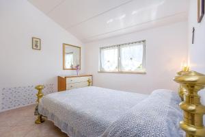 Habitación blanca con cama y ventana en Ferienwohnung in bester Lage, nahe dem Meer, en Barbariga