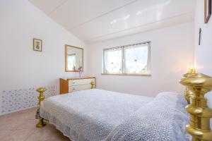 a white bedroom with a bed and a window at Ferienwohnung in bester Lage, nahe dem Meer in Barbariga