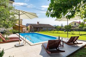 einen Pool mit 2 Stühlen und einem Sonnenschirm in der Unterkunft Casa Luigia in Pula