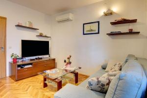 a living room with a blue couch and a tv at Appartement Tiffany in Ližnjan