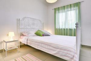 a bedroom with a white bed with a green curtain at Appartement Tiffany in Ližnjan