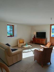 ein Wohnzimmer mit einem Sofa, Stühlen und einem TV in der Unterkunft Grange moderne près de Rennes avec jolie vue ! in Gévezé