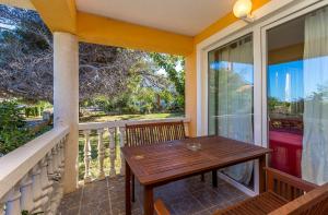 een veranda met een houten tafel op een balkon bij Ferienwohnung mit großem Pool nur 500 Meter bis zum Kieselstrand mit Klima, WLAN, Terrasse, Grillplatz in Ližnjan