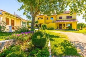 a yellow house with a tree and some flowers at Sonniges Ferienhaus inmitten grüner Natur in Grandići