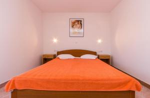 メドゥリンにあるFerienwohnung nur 700 Meter bis zum Sandstrand mit Pool, Küche, Bad, Balkon, BBQのオレンジ色の毛布が掛けられたベッドのある寝室 +13枚の写真