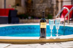 a bottle of wine and two glasses next to a swimming pool at Ferienwohnung nur 700 Meter bis zum Sandstrand mit Pool, Küche, Bad, Balkon, BBQ in Medulin
