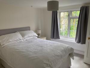 a white bed in a bedroom with a window at Bryntirion Farmhouse Apartment with Hot Tub in Llanfair Caereinion