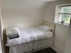 a small bedroom with a bed with white sheets and a window at Bryntirion Farmhouse Apartment with Hot Tub in Llanfair Caereinion