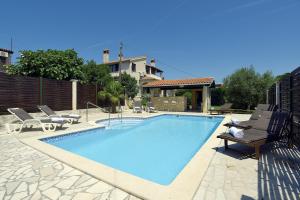 a swimming pool with chairs and a house at Einzigartige Villa nur 1 km bis zum Strand mit privatem Pool, BBQ, Klima, WLAN in Ližnjan