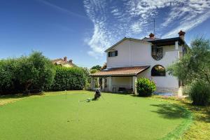 a person is playing golf on the yard of a house at Einzigartige Villa nur 1 km bis zum Strand mit privatem Pool, BBQ, Klima, WLAN in Ližnjan