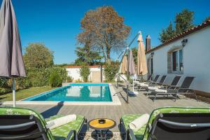 a swimming pool with chairs and umbrellas next to a house at Oberhalb des Limfjords liegt diese Ferienwohnung mit Pool, Terrrasse und Grillplatz in Barat