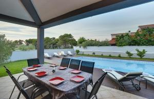 un patio con mesa de comedor y sillas y piscina en Villa Entini, en Vinkuran