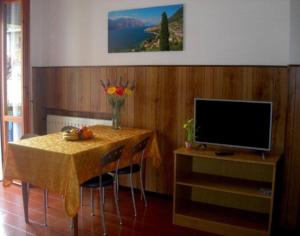 uma sala de jantar com uma mesa e uma televisão em Tignale - Appartement VISTA BLU 107 - Ferienwohnung am Gardasee mieten em Tignale