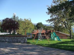 un parco giochi con scivolo di fronte a una casa di Ferienhäuschen CLAUDIO mit Pool in Tignale a Olzano