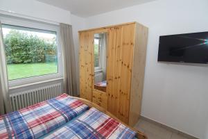 a bedroom with a bed and a tv and a window at Bungalow Tilla in Norddeich