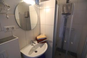 Un baño con lavabo, espejo y ducha. en Bungalow Tilla, en Norddeich 23 fotos más